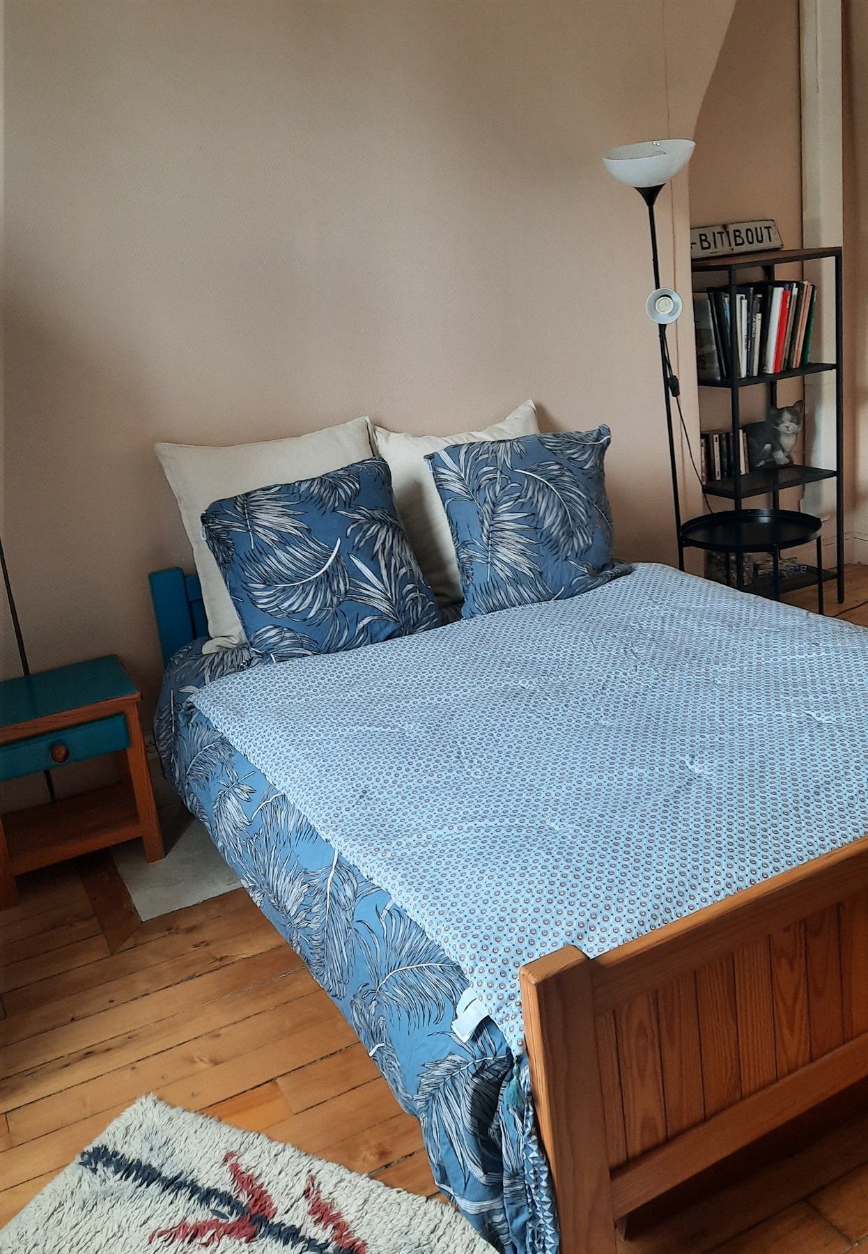 Chambre avec lit double, linge bleu et parquet