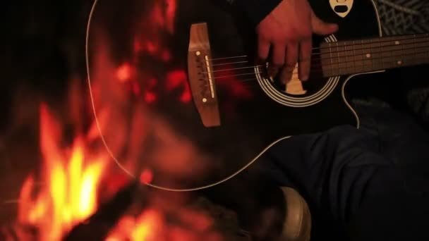 Une guitare jouée au coin d'un feu de camp, la nuit